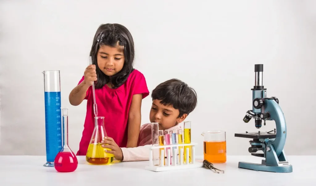 Children performing a science experiment using test tubes and colorful liquids at a table.